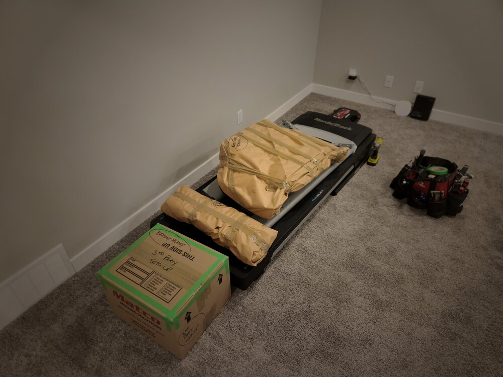 A treadmill broken down, wrapped, with hardware bagged and boxed alongside it