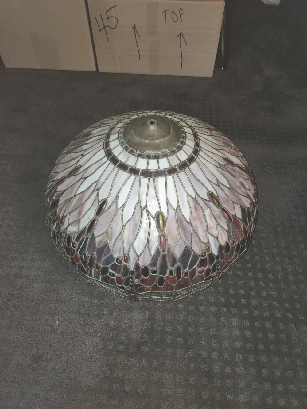 A stained-glass Tiffany lamp shade resting on a pad before crating
