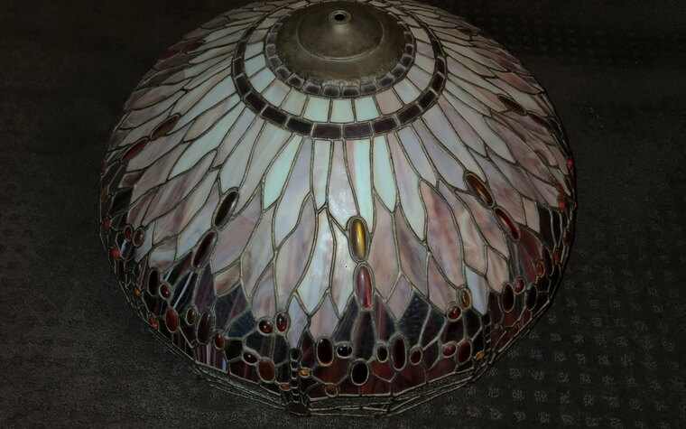 A stained-glass Tiffany lamp shade resting on a pad before crating