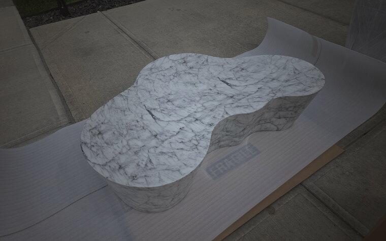 A figure-eight Carrara marble table top on protective paper, labeled fragile