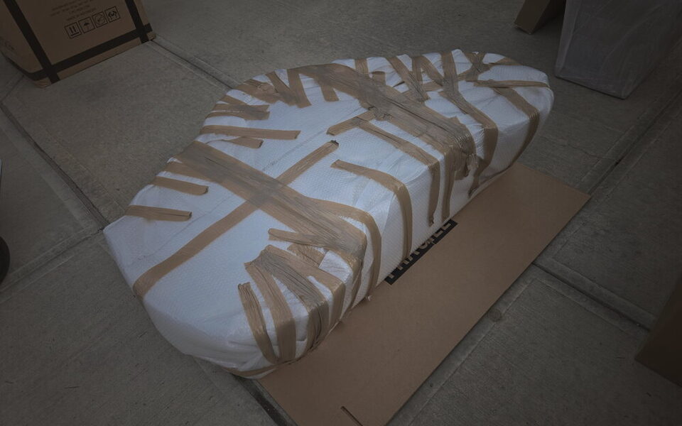 A figure-eight Carrara marble table top wrapped and taped, braced flat for transport.