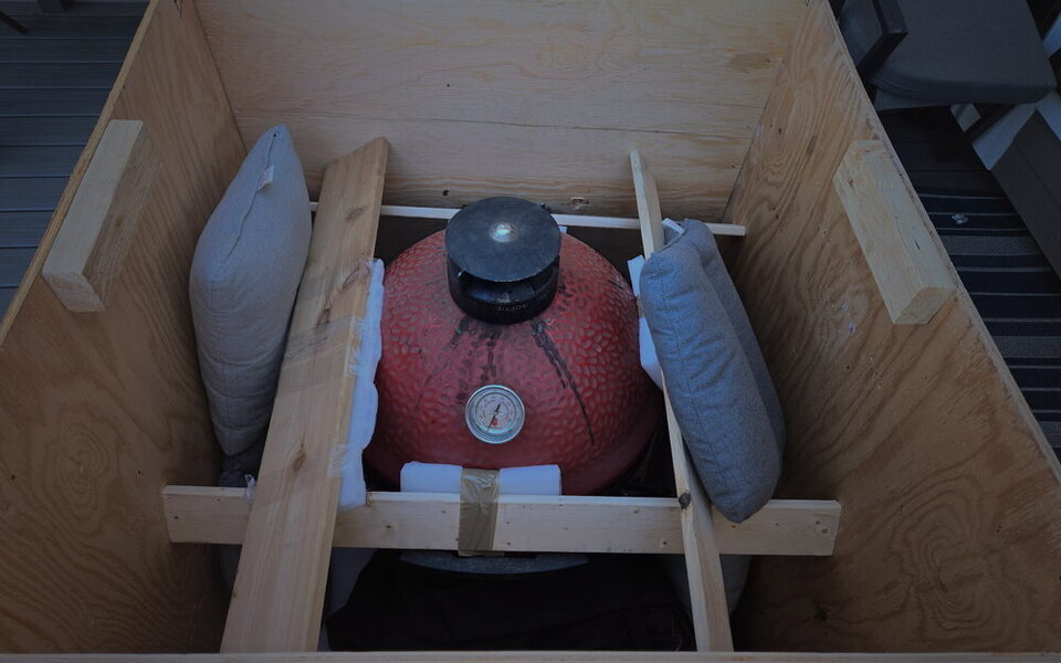 A red ceramic Kamado grill cushioned and cross-braced inside a custom wood crate.