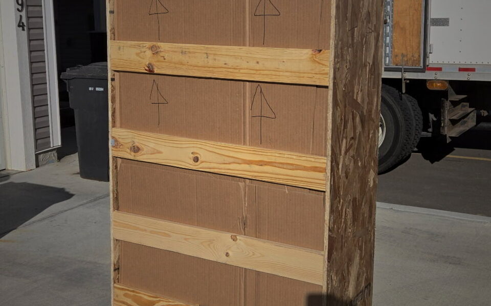 A tall, narrow custom crate built around an oversized vertical piece.